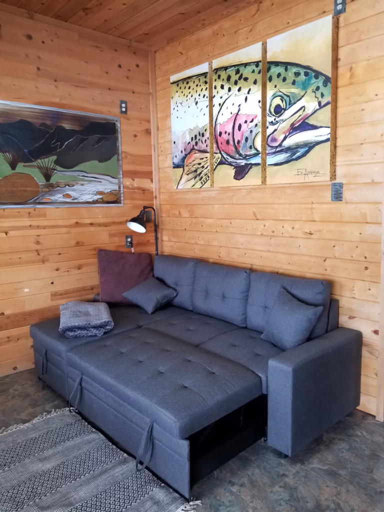 Sleeper sofa and trout art in the living area of the Gallatin River Cabin, Montana