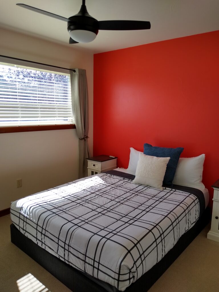 Bedroom with ceiling fan and red accent wall at the Northside Condo in Bozeman
