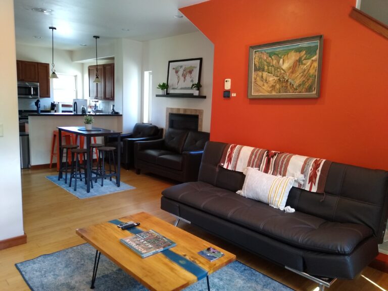 Living room with leather sofa and orange accent wall at the Northside Condo in Bozeman