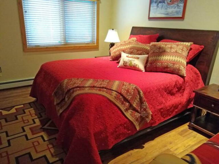 Bedroom with red bedding and western decor at the Flying J Bunkhouse, Montana